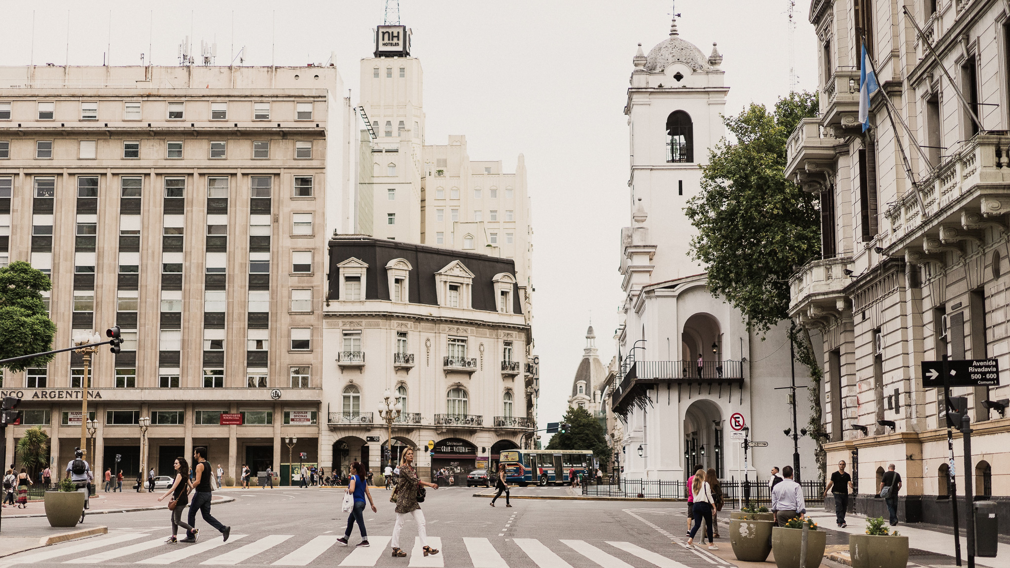 A crossway in Buenos Aires. The buildings are in the background. Pleople is crossing the street.