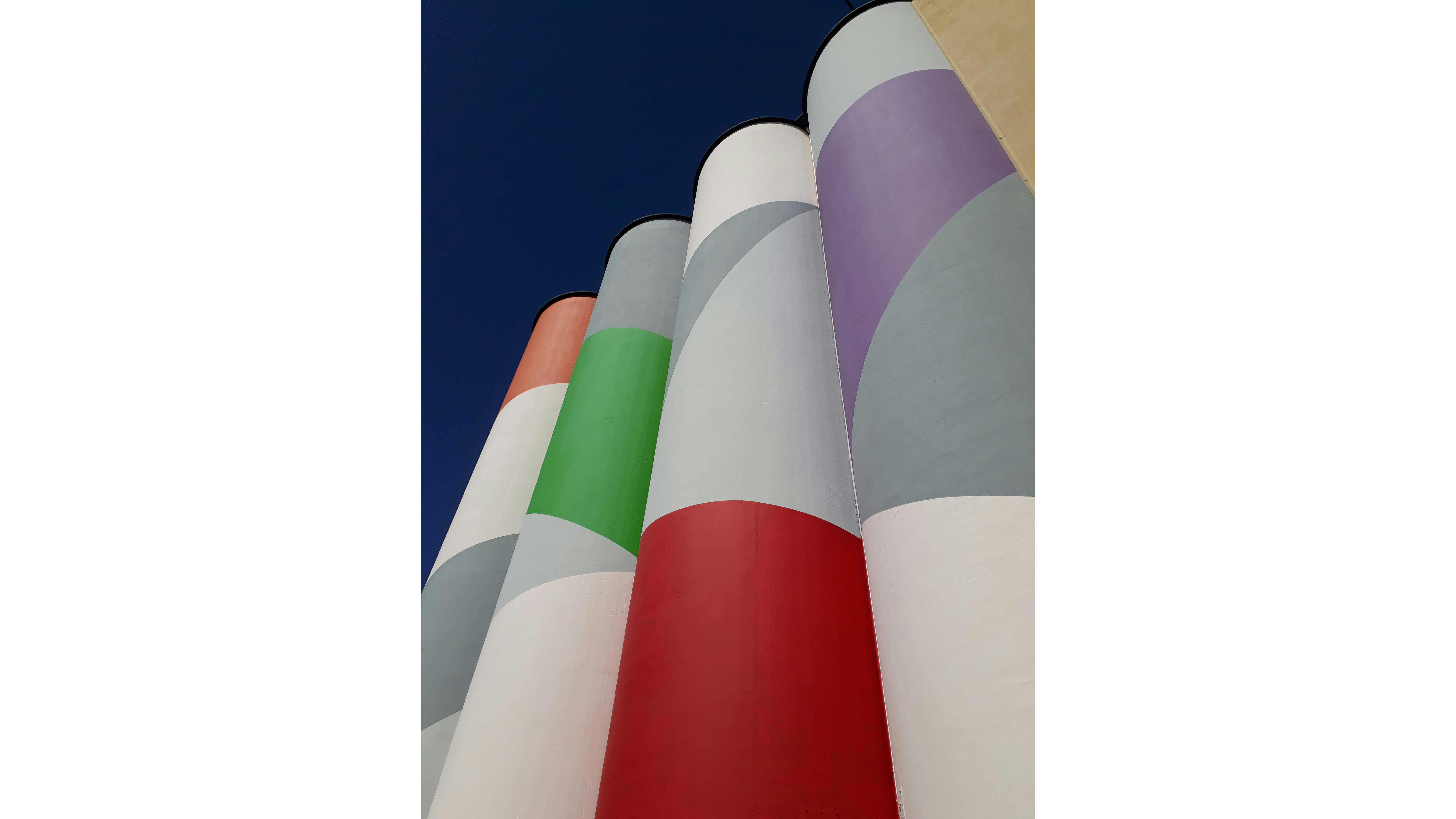 Silos painted in various colors, set against a beautiful blue sky.