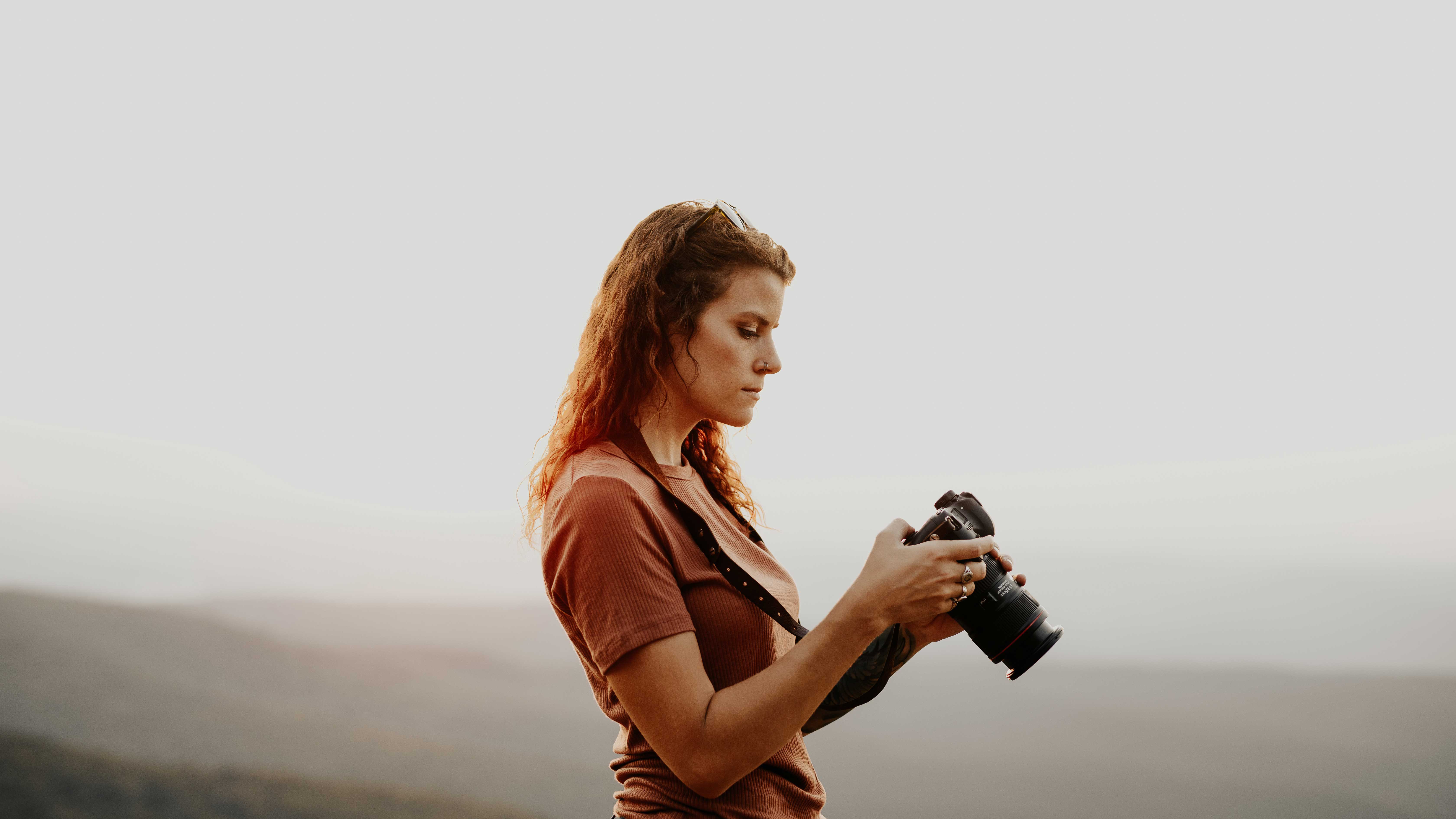 A woman looking at her camera after taking a picture in a foggy landscape.